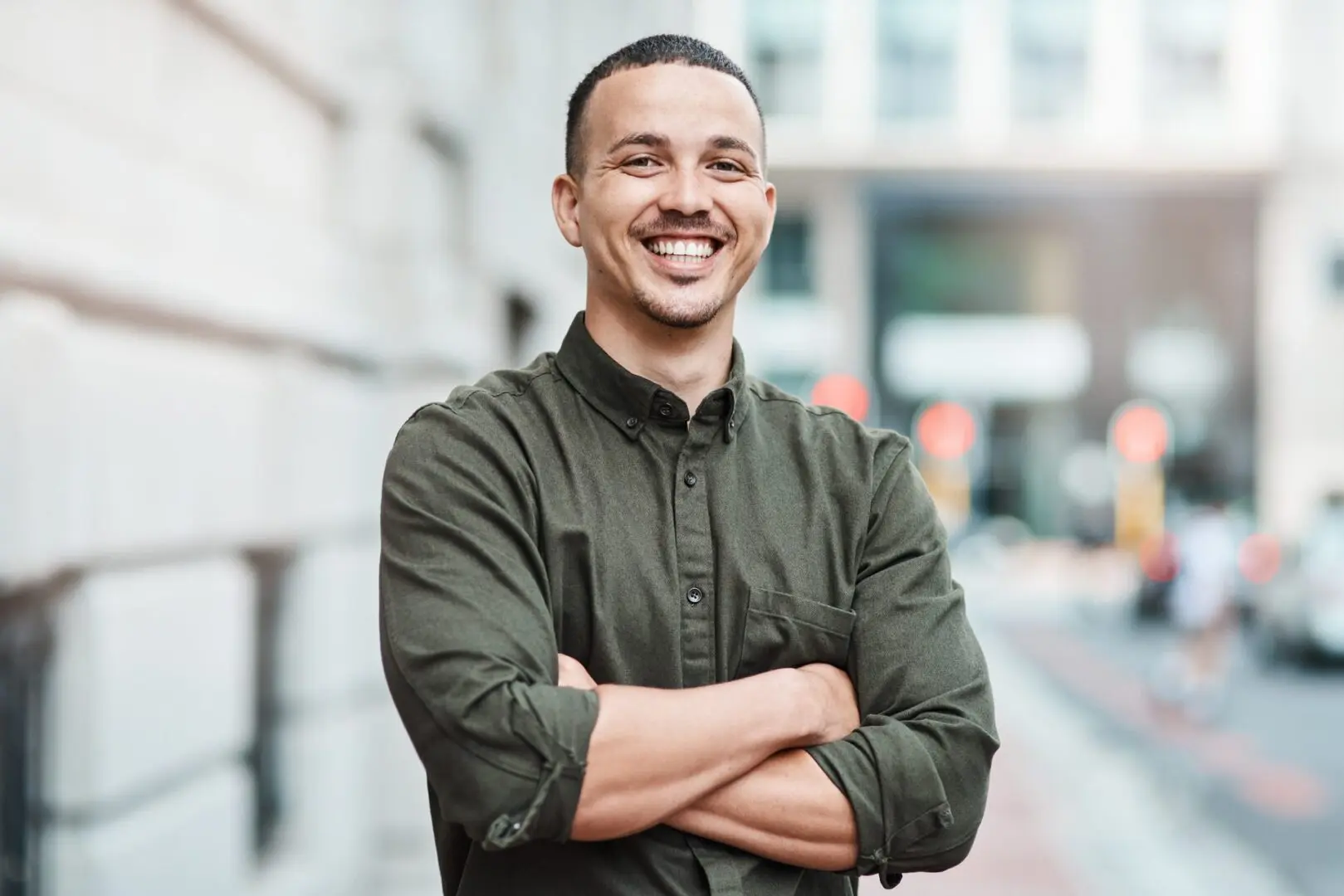 A man standing on the side of a road with his arms crossed.