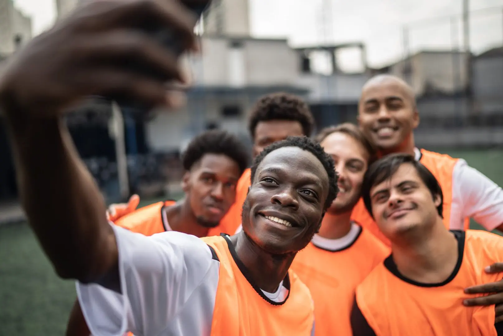 A group of young men taking a picture with their cell phone.