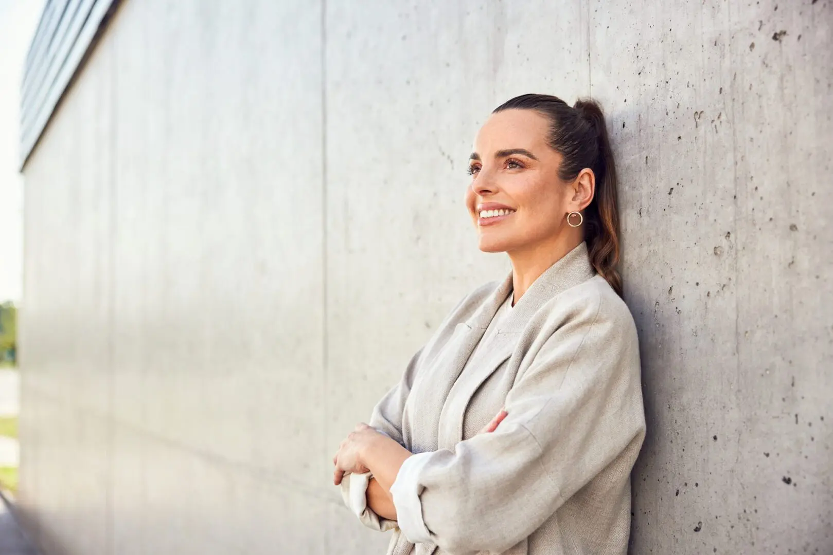 A woman leaning against the wall smiling.